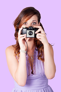Surprised woman taking picture with old camera