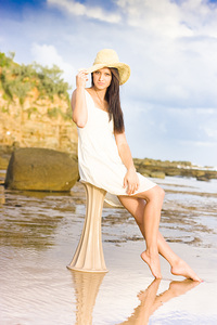Elegant Woman With Hat Sitting At The Beach