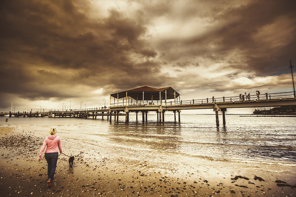 Woman walking dog on stormy beach Print