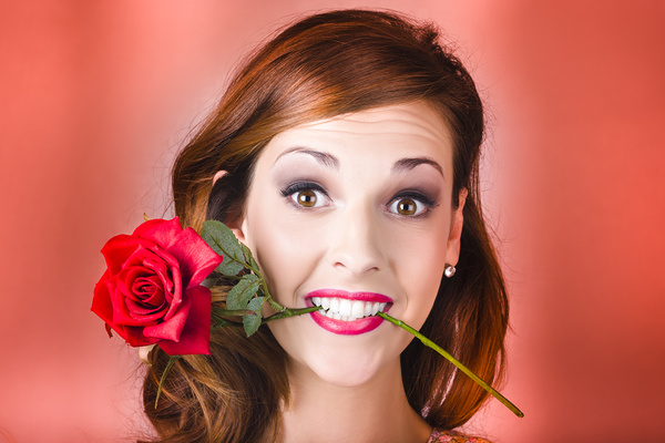 Woman gripping red rose between her teeth Print