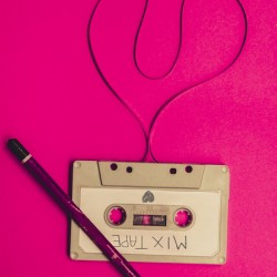 audio cassette with heart shape tape on pink background
