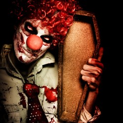 Evil Horrible Clown Holding Coffin In Darkness
