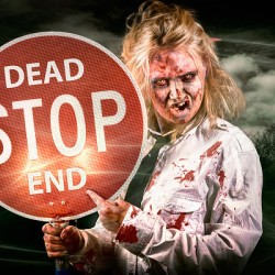 Halloween portrait. Scary zombie holding stop sign