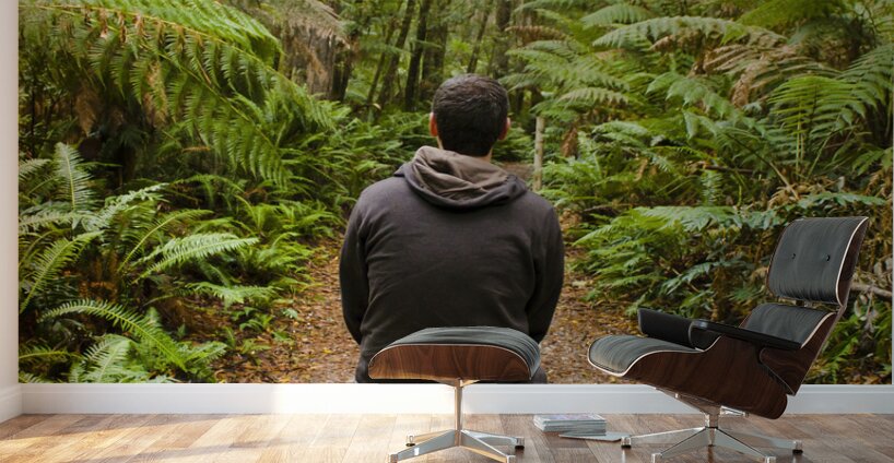 Travel man sitting in a green lush fern forest Wall Murals